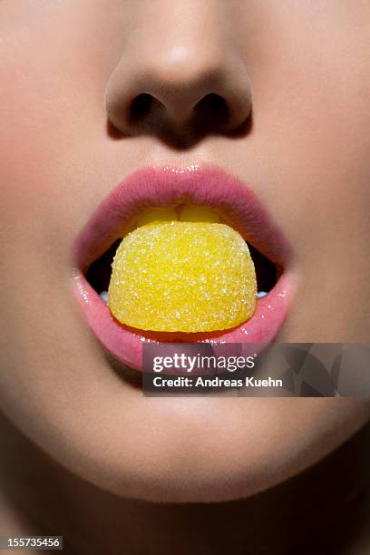 yellow gumdrop in young woman's mouth, cropped. - candy lips stock pictures, royalty-free photos & images
