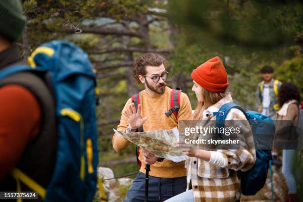 junges wandererpaar, das sich unterhält, während er eine karte im wald analysiert. - orientierungslauf landkarte gruppe stock-fotos und bilder