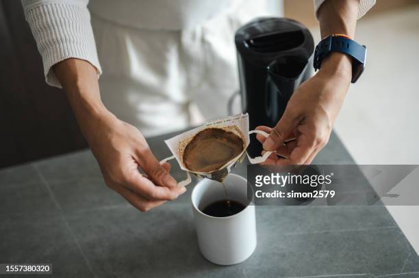 making coffee with drip coffee bag in a beige cup on white marble table - drip bag stockfoto's en -beelden