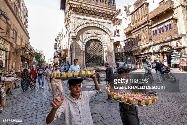 Boys sell sweet pastries to pedestrians outside the 18th-century Ottoman-period Sabil-Kuttab of Abd al-Rahman Katkhuda along Islamic Cairo's landmark...