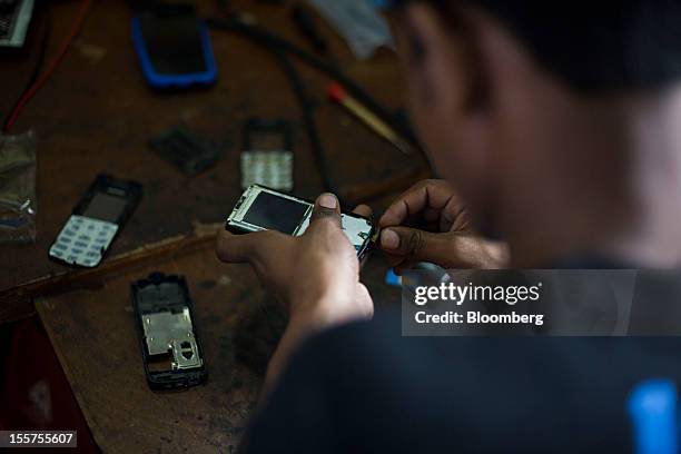 Man repairs a mobile phone in Mumbai, India, on Tuesday, Nov. 6, 2012. Reserve Bank of India Governor Duvvuri Subbarao lowered the RBI’s forecast for...