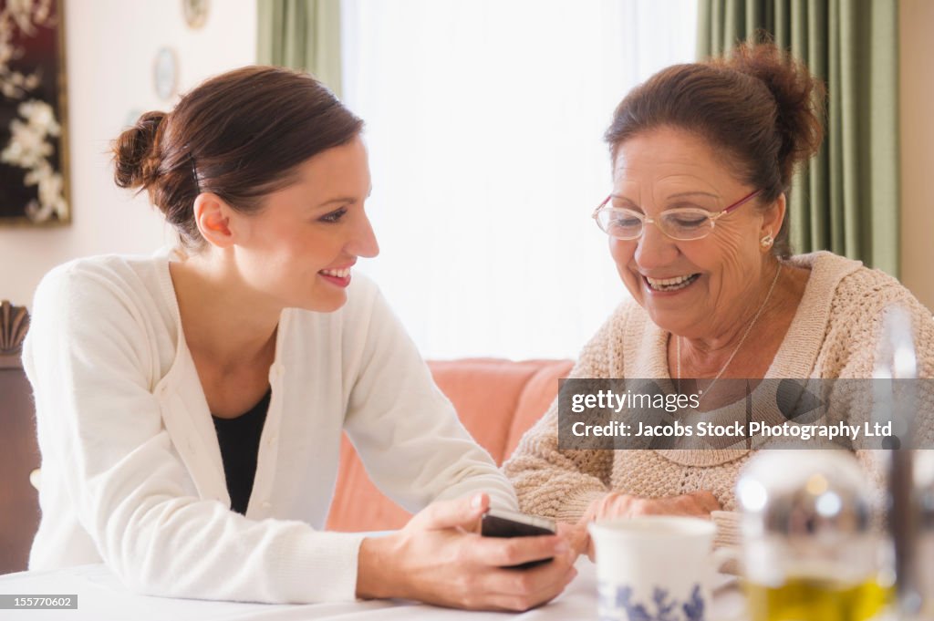 Hispanic woman showing cell phone to grandmother