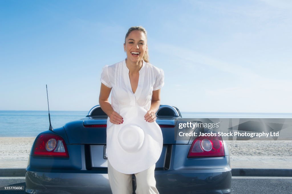 Hispanic woman standing near car at beach