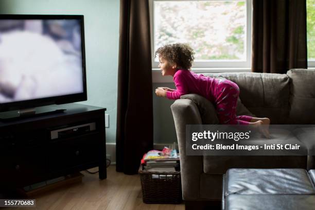 mixed race girl watching television - kid leaning stock pictures, royalty-free photos & images