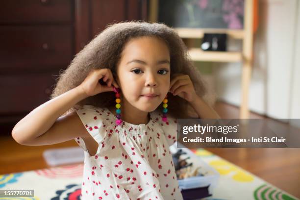 mixed race girl trying on earrings - earrings stock pictures, royalty-free photos & images