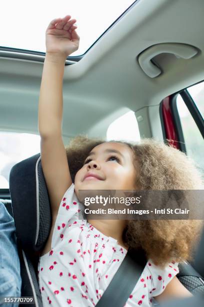 mixed race girl sitting in car seat with arm out window - sunroof stock pictures, royalty-free photos & images