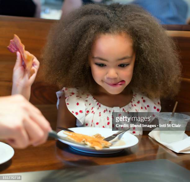 mixed race girl eating breakfast in restaurant - happy family eating photos et images de collection