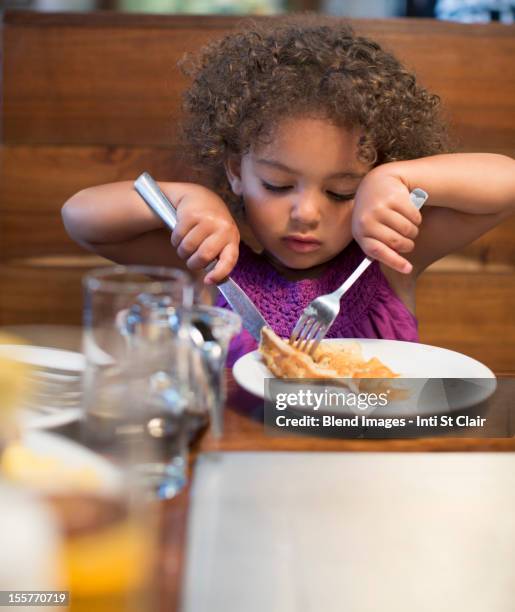 mixed race girl eating breakfast in restaurant - restaurant kids stockfoto's en -beelden