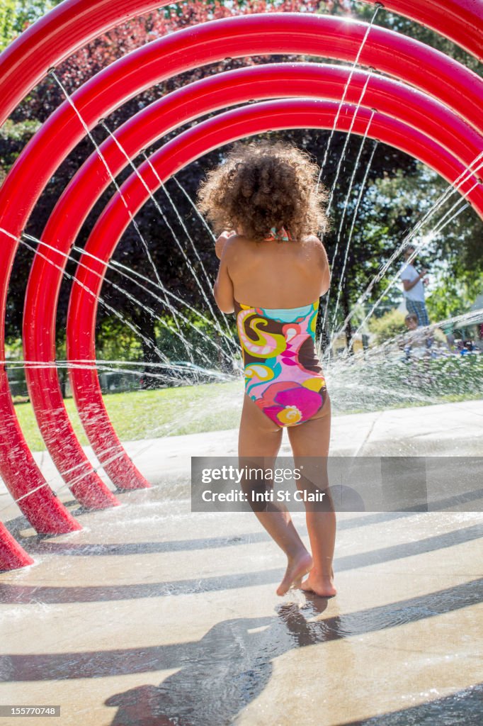 Mixed race girl playing in fountain