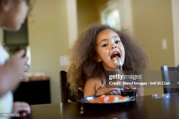 mixed race girl eating dinner - girls licking girls stockfoto's en -beelden