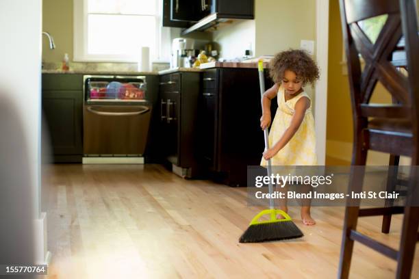 mixed race girl sweeping kitchen floor - child sweeping stock pictures, royalty-free photos & images