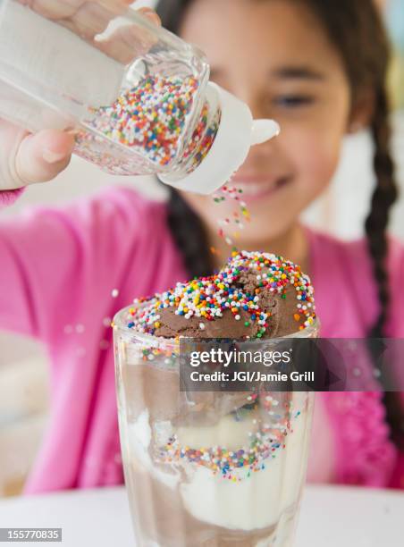 mixed race girl putting sprinkles on ice cream - strooisels stockfoto's en -beelden