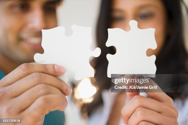 mixed race couple holding puzzle pieces - things that go together stock pictures, royalty-free photos & images