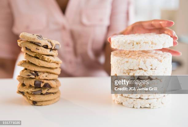 cape verdean woman stacking cookies and rice cakes - temptation stock-fotos und bilder