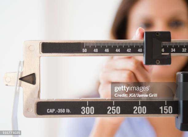cape verdean woman weighing herself - preocupación por el cuerpo fotografías e imágenes de stock