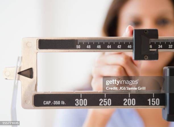 cape verdean woman weighing herself - weight gain foto e immagini stock