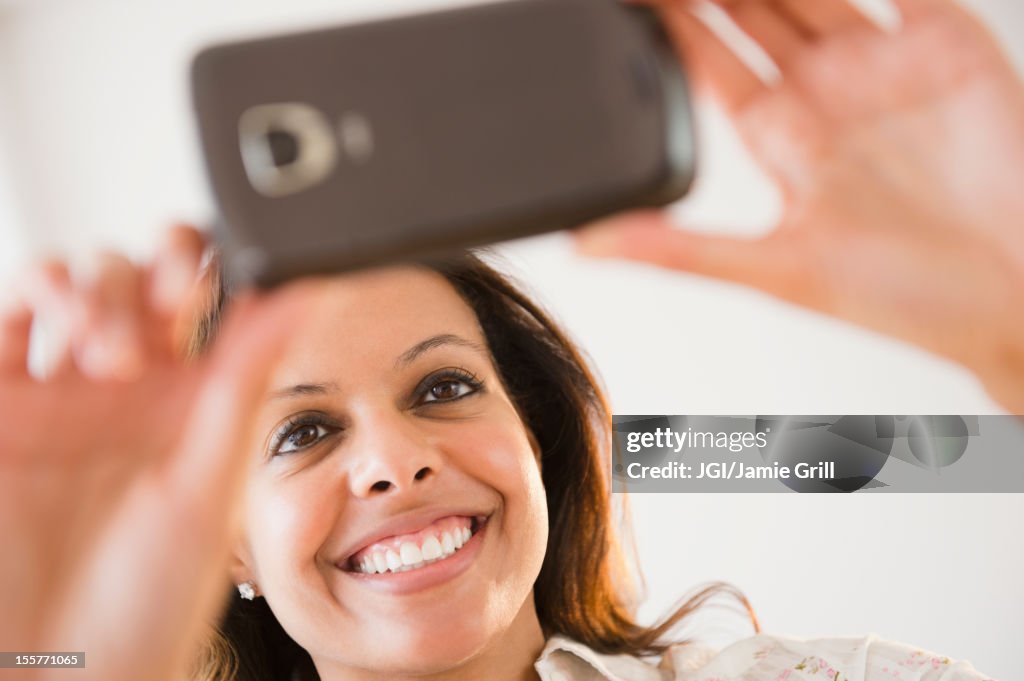 Cape Verdean woman taking photograph with cell phone