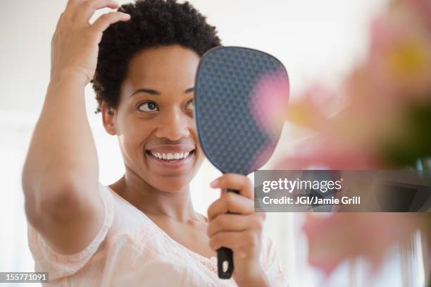 african american woman checking hair in mirror - woman short hair stock pictures, royalty-free photos & images