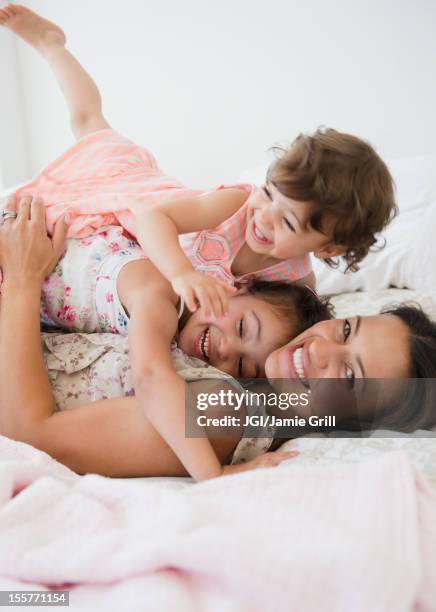 mother and daughters laying on bed - seize the day bed stock pictures, royalty-free photos & images