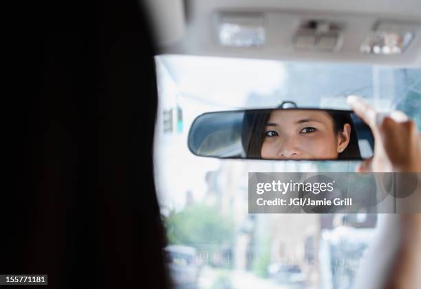 asian woman adjusting rear-view mirror - car rear view mirror stock pictures, royalty-free photos & images