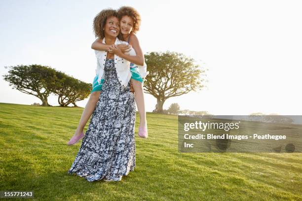 african american mother giving daughter a piggyback ride - おんぶ ストックフォトと画像