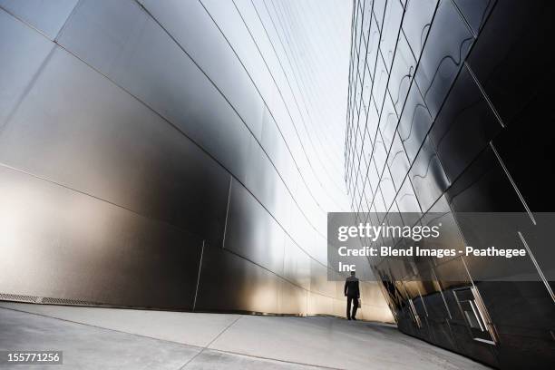 businessman walking in urban alley - distante stock pictures, royalty-free photos & images