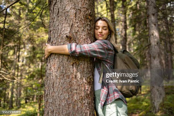 young female tourist enjoying while embracing the tree in nature. - tree hugging stock pictures, royalty-free photos & images