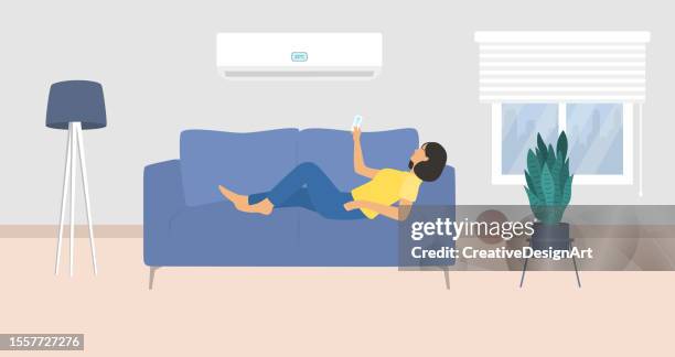 young woman lying down on couch and turning on air conditioner with remote controller - living room with people stock illustrations