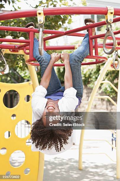 young woman hanging n monkey bars - hanging monkey bars stock pictures, royalty-free photos & images
