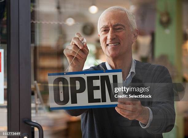 senior man hanging open sign - open sign on door stock pictures, royalty-free photos & images