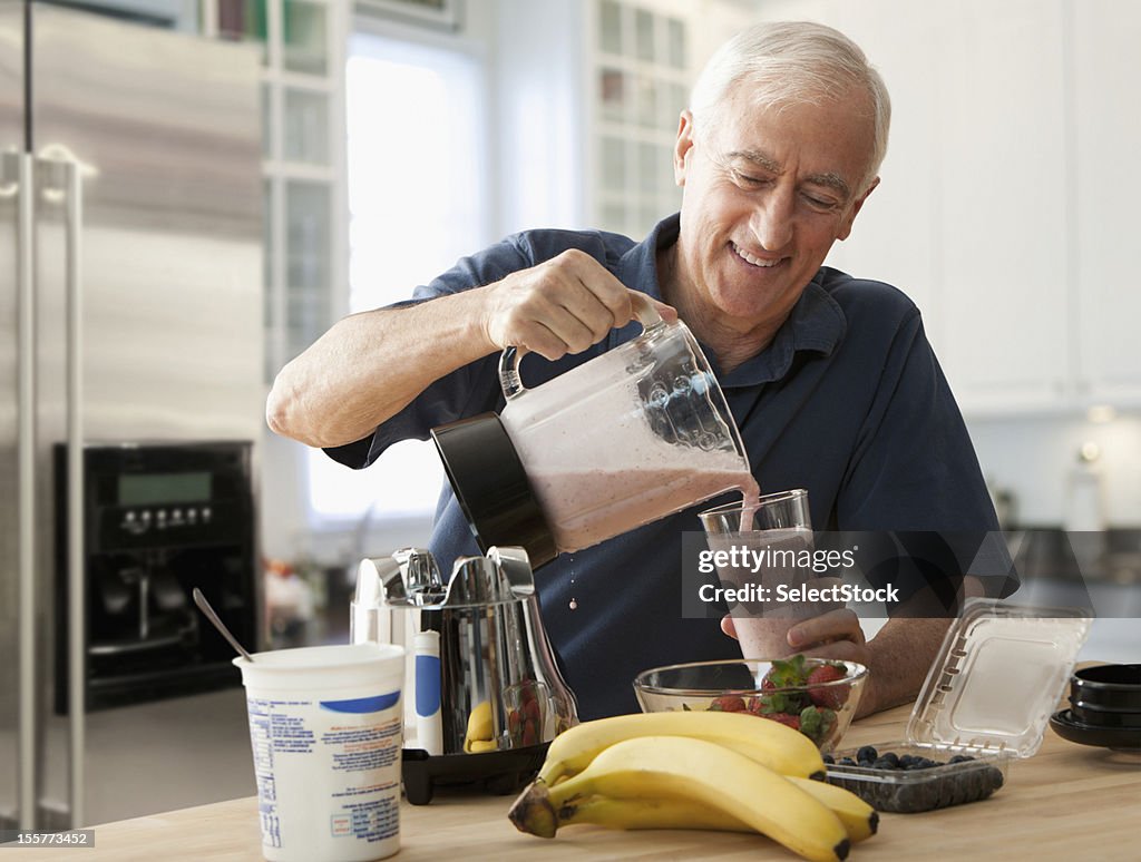 Alter Mann gießen Glas Früchte-smoothie