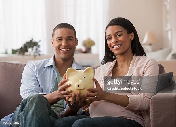 junge eltern, hält sparschwein - couple saving piggy bank stock-fotos und bilder