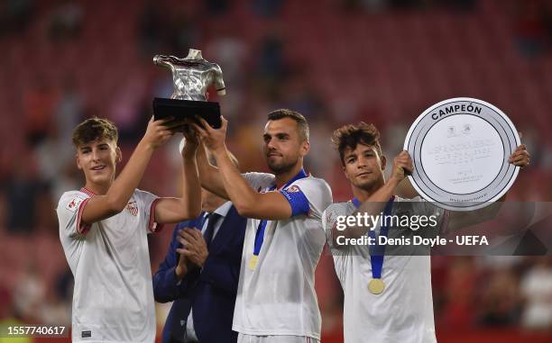 Aitor Antonio Puerta, son of former Sevilla player Antonio Puerta, Joan Jordan and Oliver Torres hold up their Antonio Puerta trophy and UEFA...