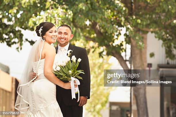 smiling hispanic bride and groom - bride and groom looking at camera stock-fotos und bilder