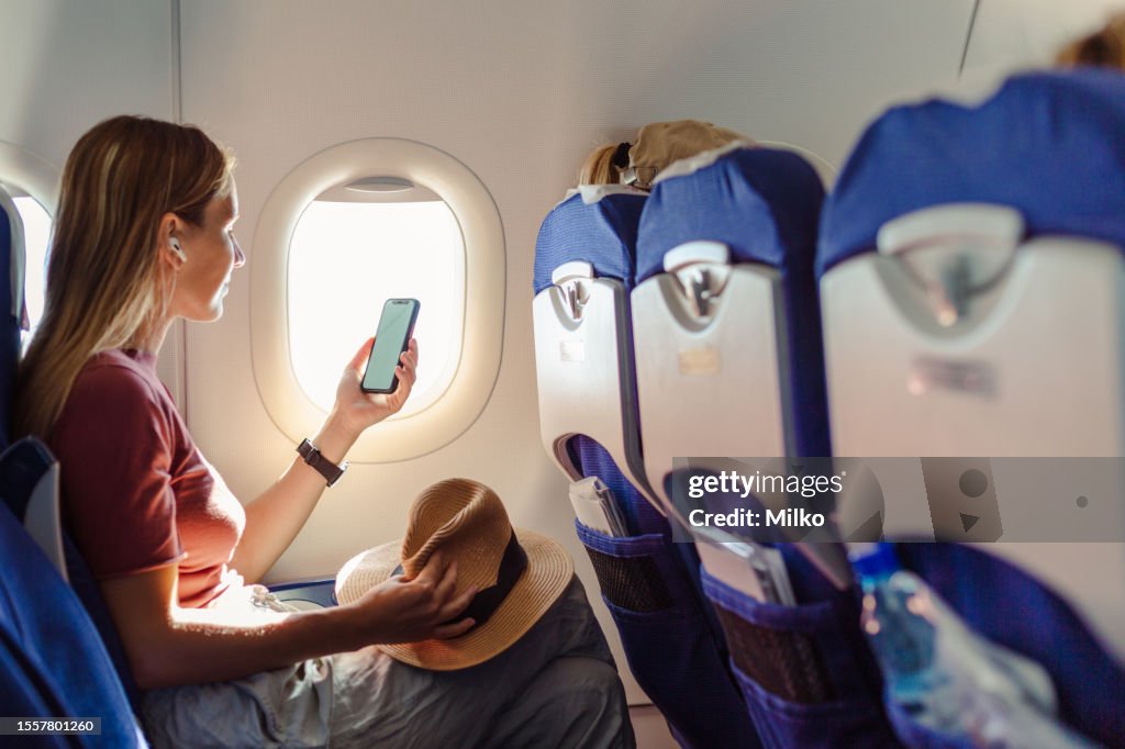 Woman in the aircraft holding smart phone with white screen