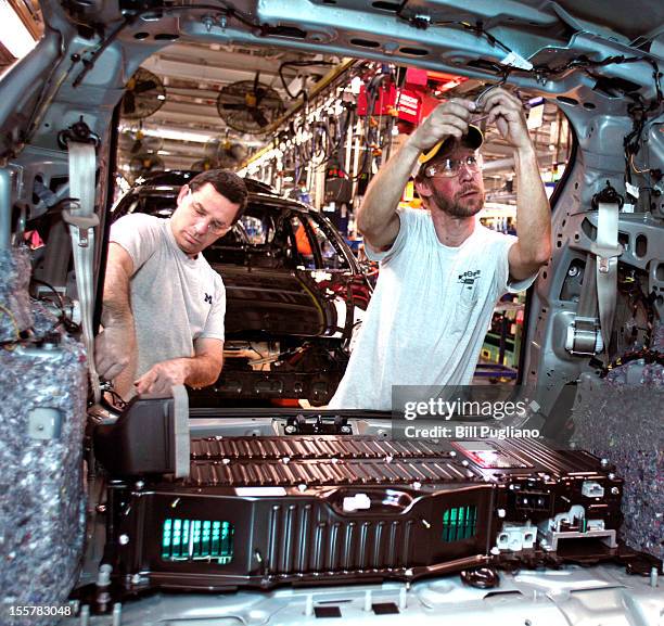 Ford workers load a battery into a Ford C-MAX plug-in hybrid vehicle at the Michigan Assembly Plant November 8, 2012 in Wayne, Michigan. The plant is...