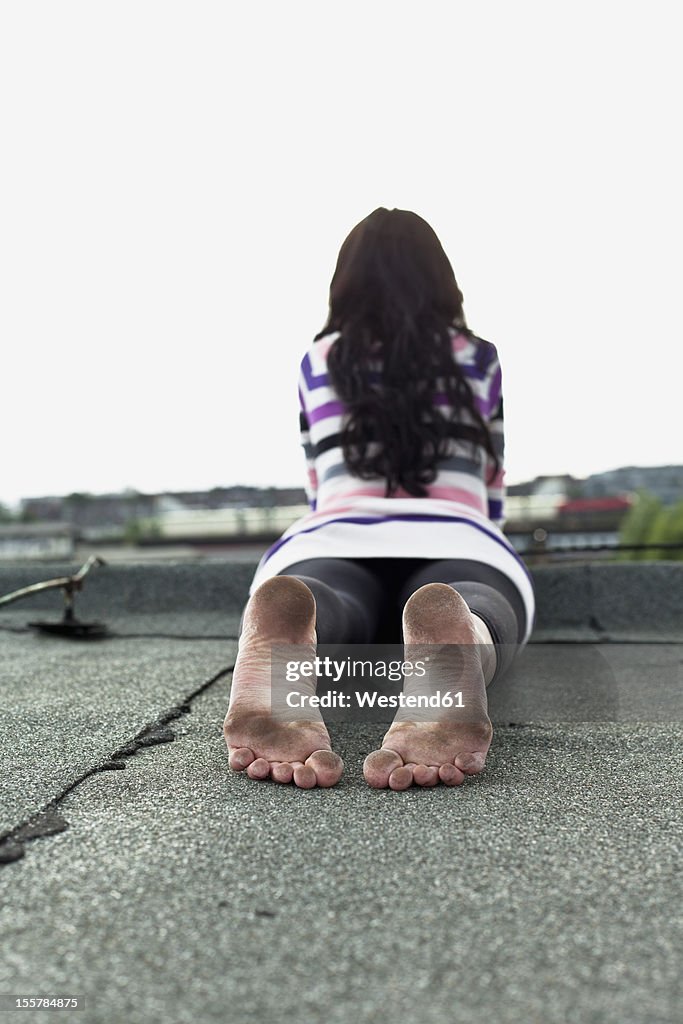 Germany, Hamburg, Young woman lying on roof