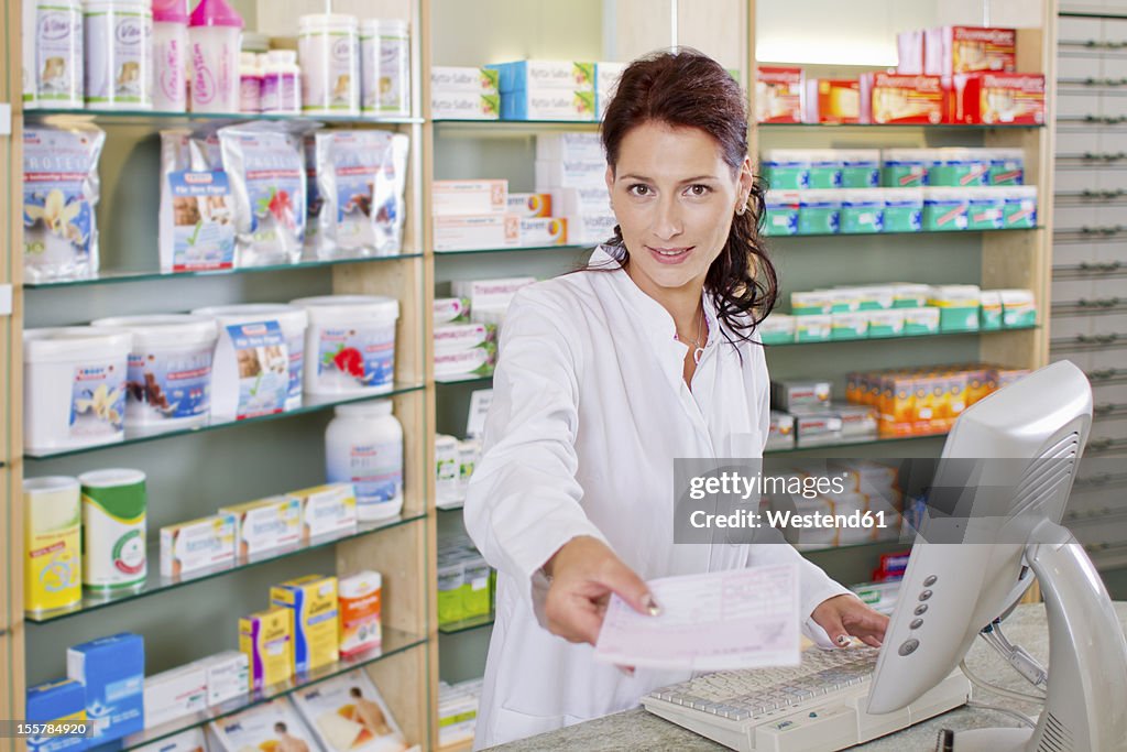 Germany, Brandenburg, Pharmacist holding prescription, smiling, portrait