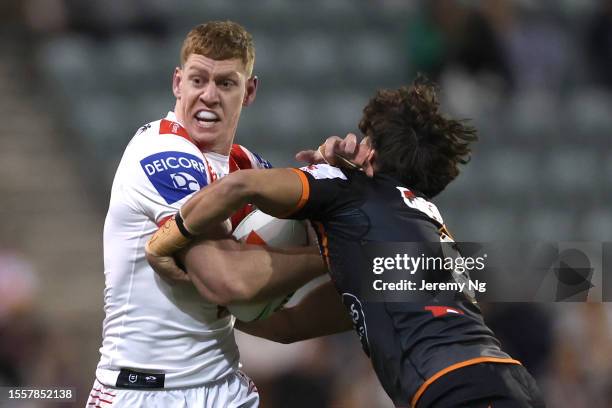 Dan Russell of the Dragons fends off Daine Laurie of the Tigers during the round 21 NRL match between St George Illawarra Dragons and Wests Tigers at...