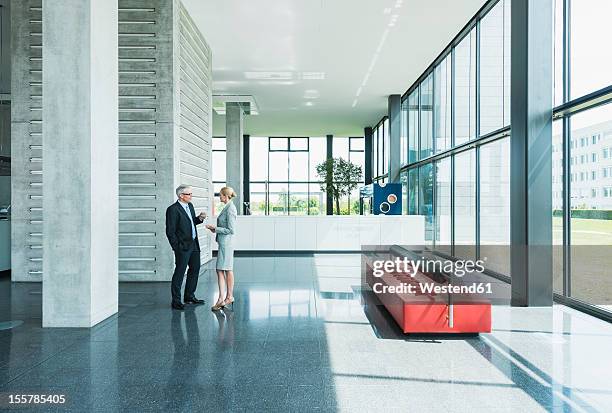 germany, stuttgart, business people having discussion at office lobby - gebäudeteil stock-fotos und bilder