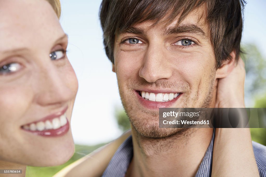 Germany, Cologne, Young couple embracing, smiling, portrait