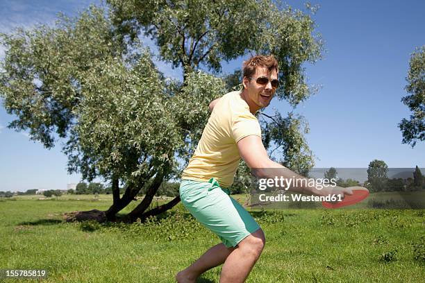 germany, north rhine westphalia, duesseldorf, mid adult man playing with frisbee, smiling - flying disc stock pictures, royalty-free photos & images