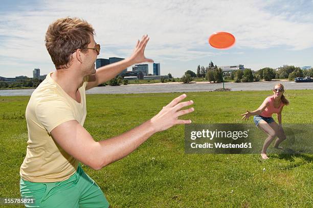 germany, north rhine westphalia, duesseldorf, couple playing with frisbee - throwing frisbee stock pictures, royalty-free photos & images