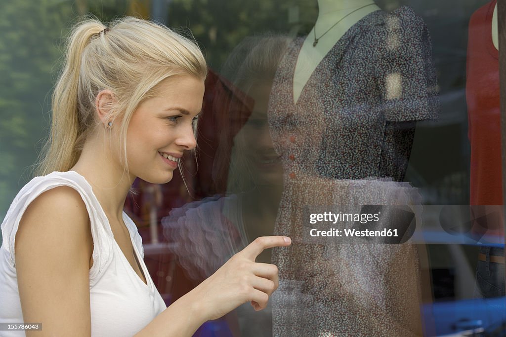 Germany, North Rhine Westphalia, Cologne, Young woman at window shopping