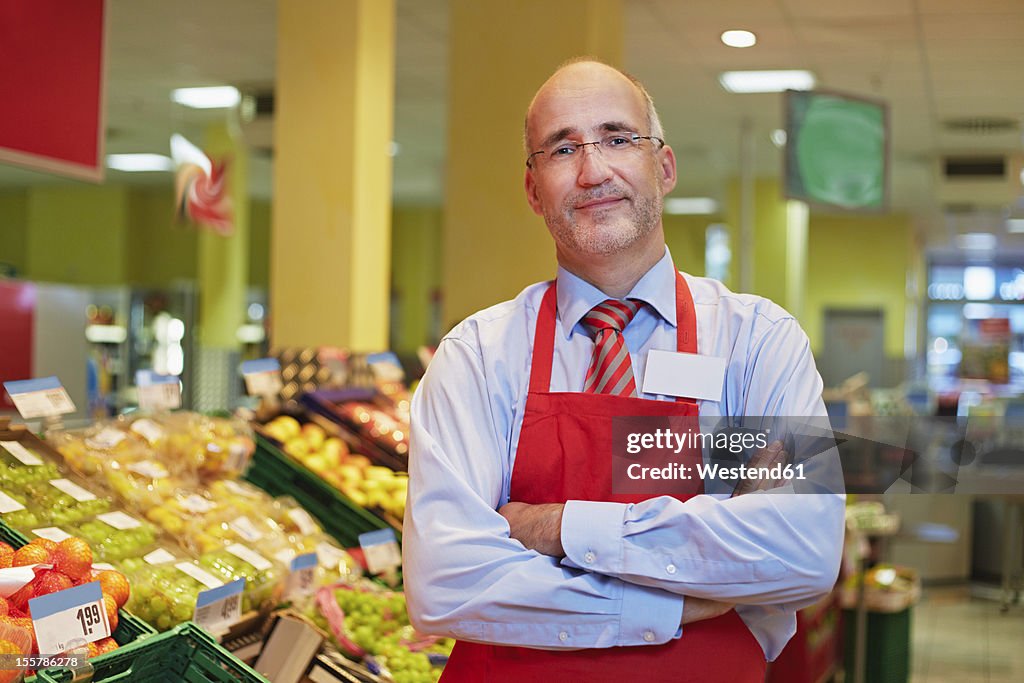 Germany, Cologne, Mature man standing in supermarket, smiling, portrait