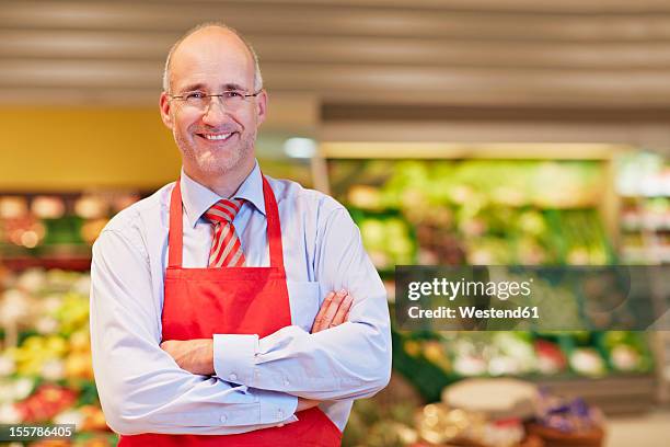 germany, cologne, mature man in supermarket, smiling, portrait - groenteboer stockfoto's en -beelden