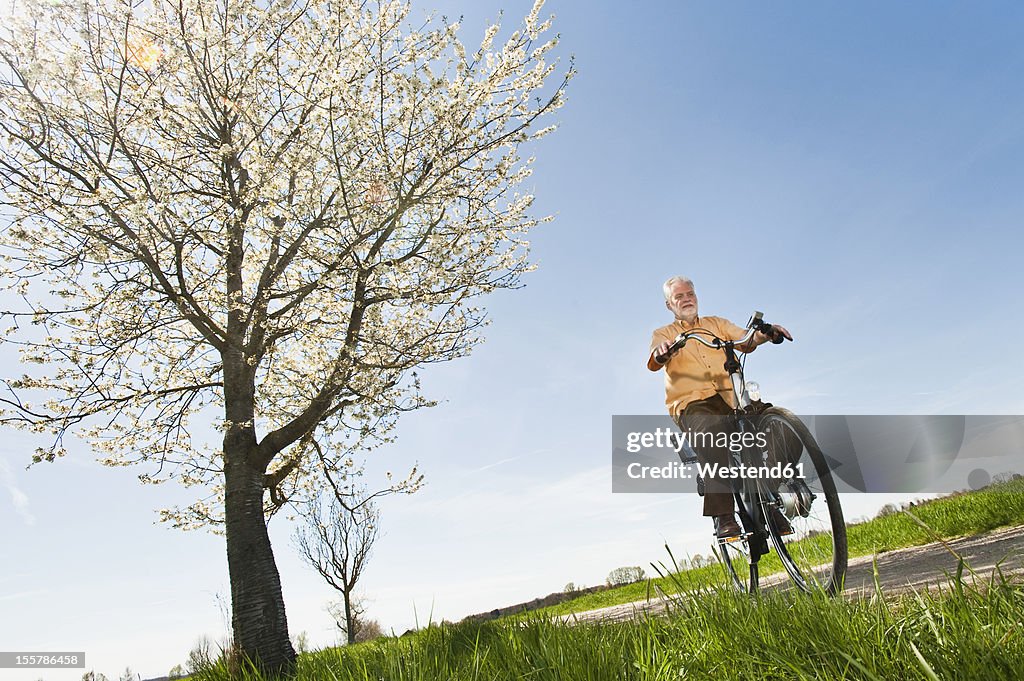 Germany, Bavaria, Senior man riding electric bicycle