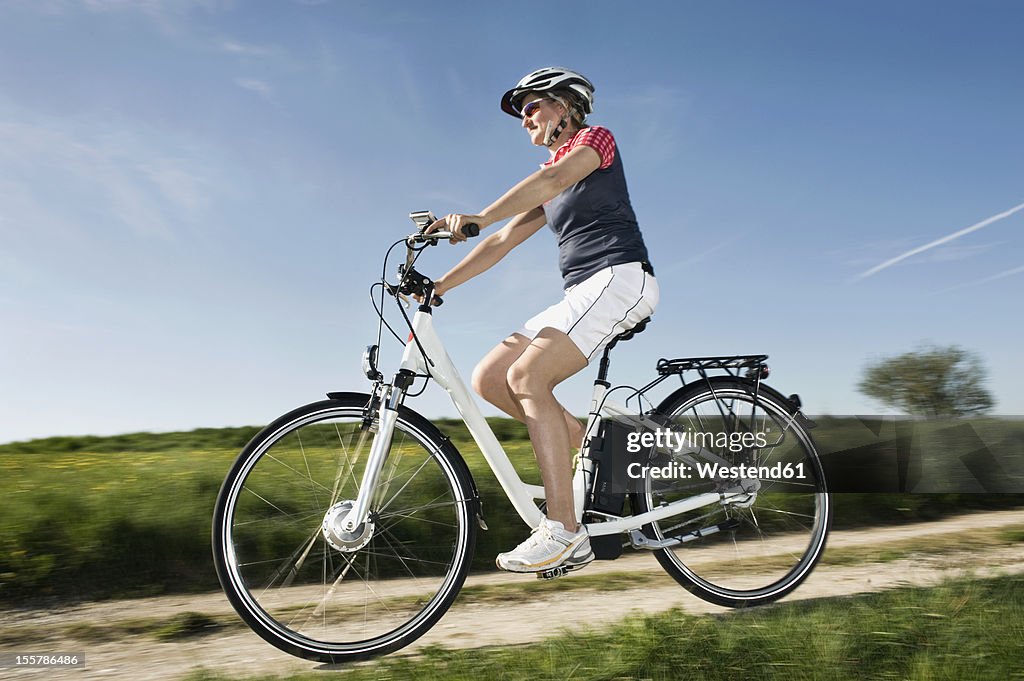 Germany, Bavaria, Mature woman riding electric bicycle