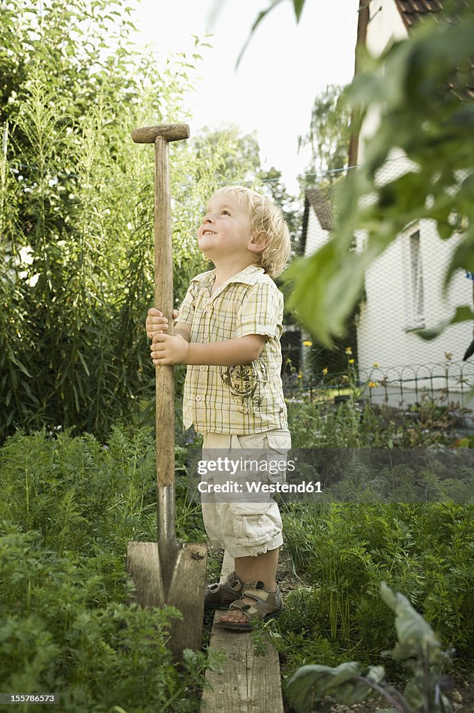 Germany, Bavaria, Boy holding shovel in garden