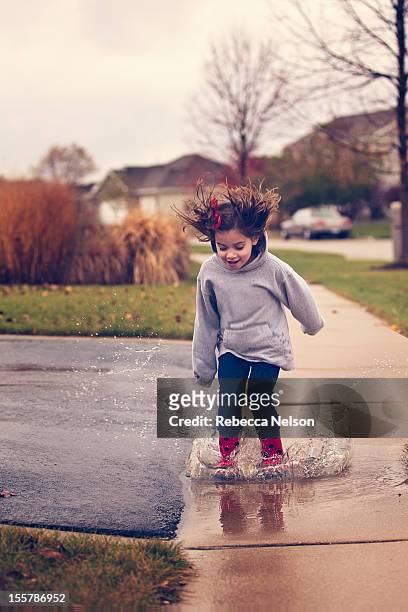 little girl jumping in rain puddle - puddle fotografías e imágenes de stock